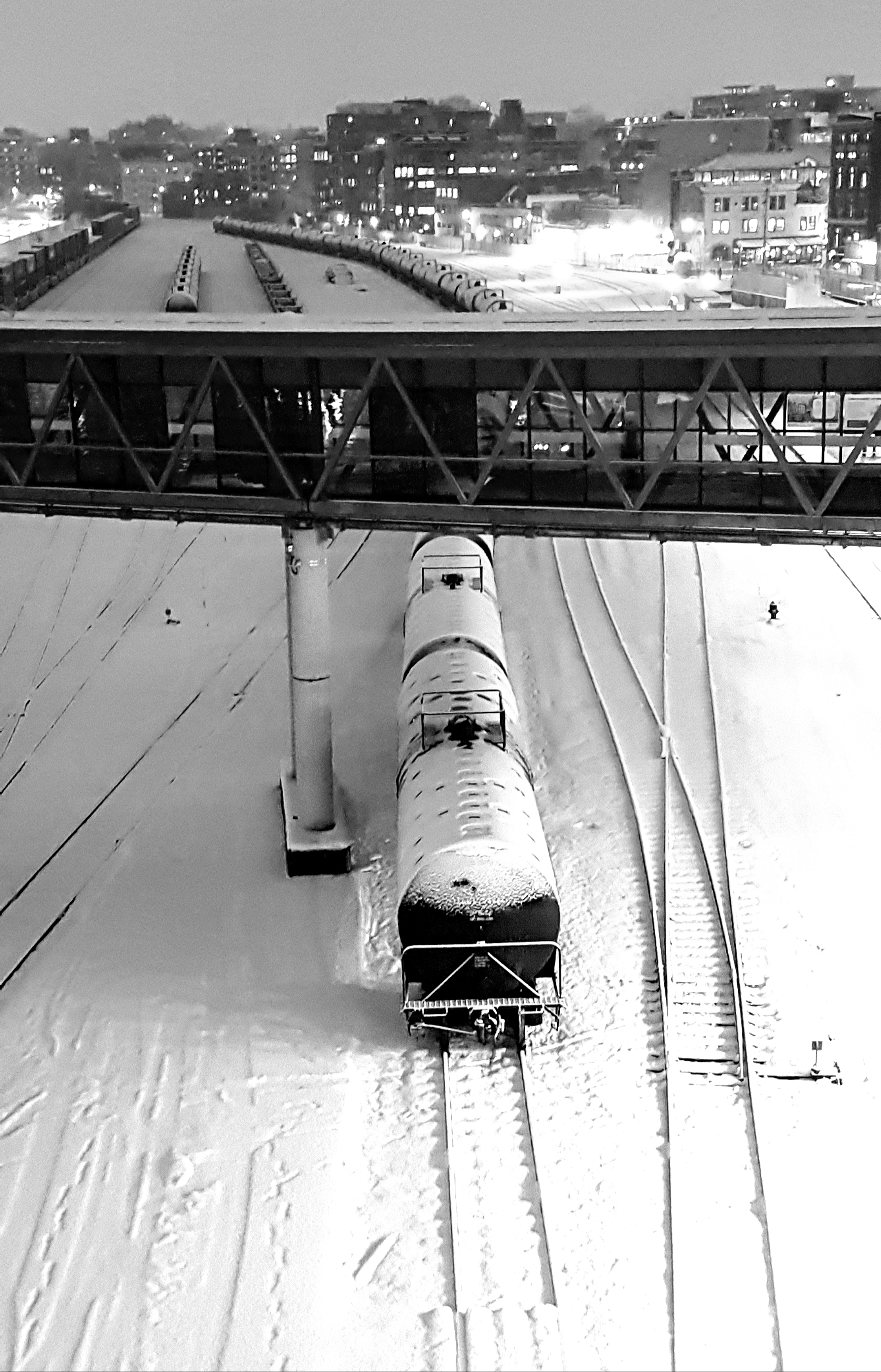 Black and white photograph of railyard and stationary train covered with snow by B.Y. Penman